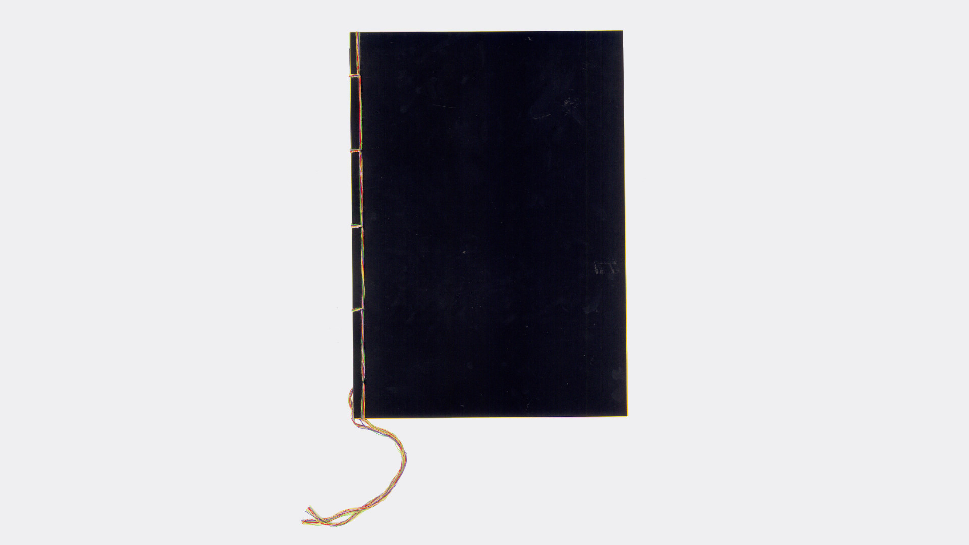 The book is closed, we can see the front cover that is plain black and the japanese binding with multicoloured threads.